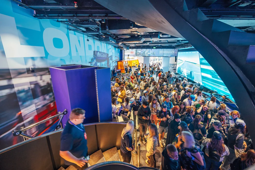 A crowded indoor space with modern architecture, vibrant lighting, and people engaged in various activities, possibly an event or exhibition.