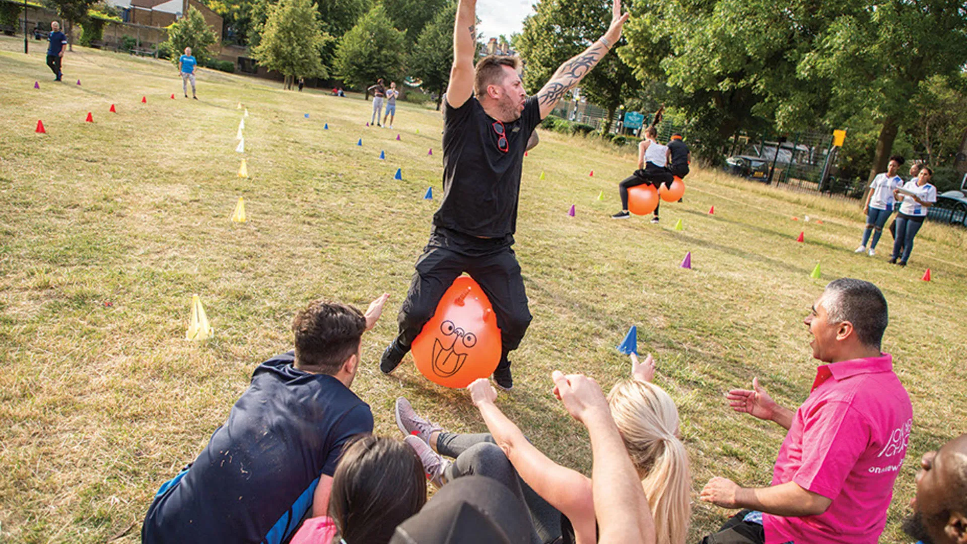 People enjoying outdoor activities with inflatable balls and cones in a park.