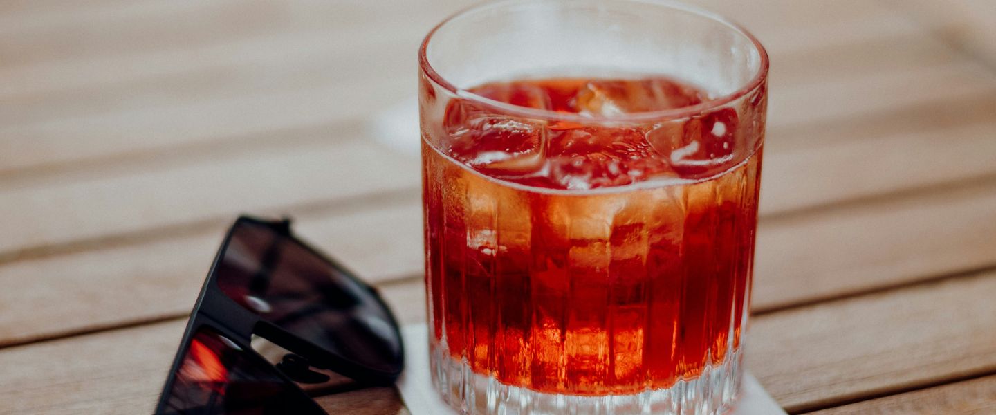 A Negroni on a table next to some sunglasses