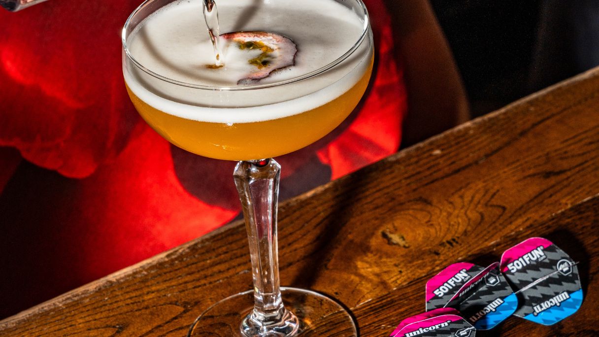 A cocktail glass next to some darts