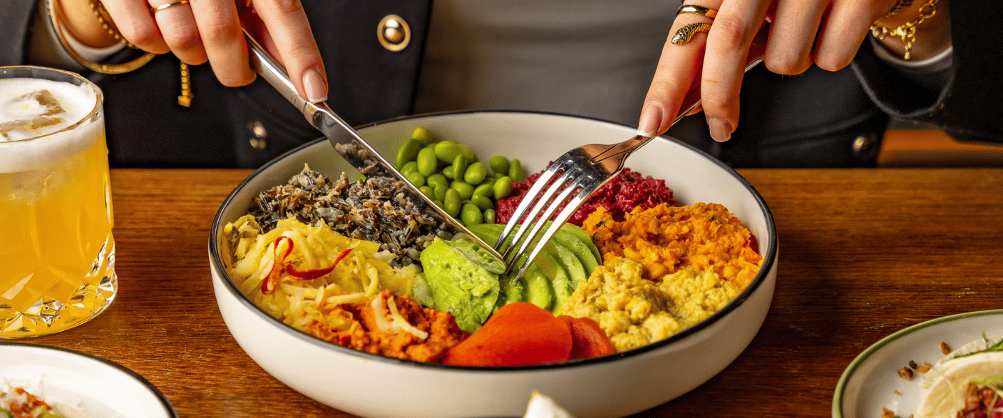 A man eating a salad bowl with a knife and fork