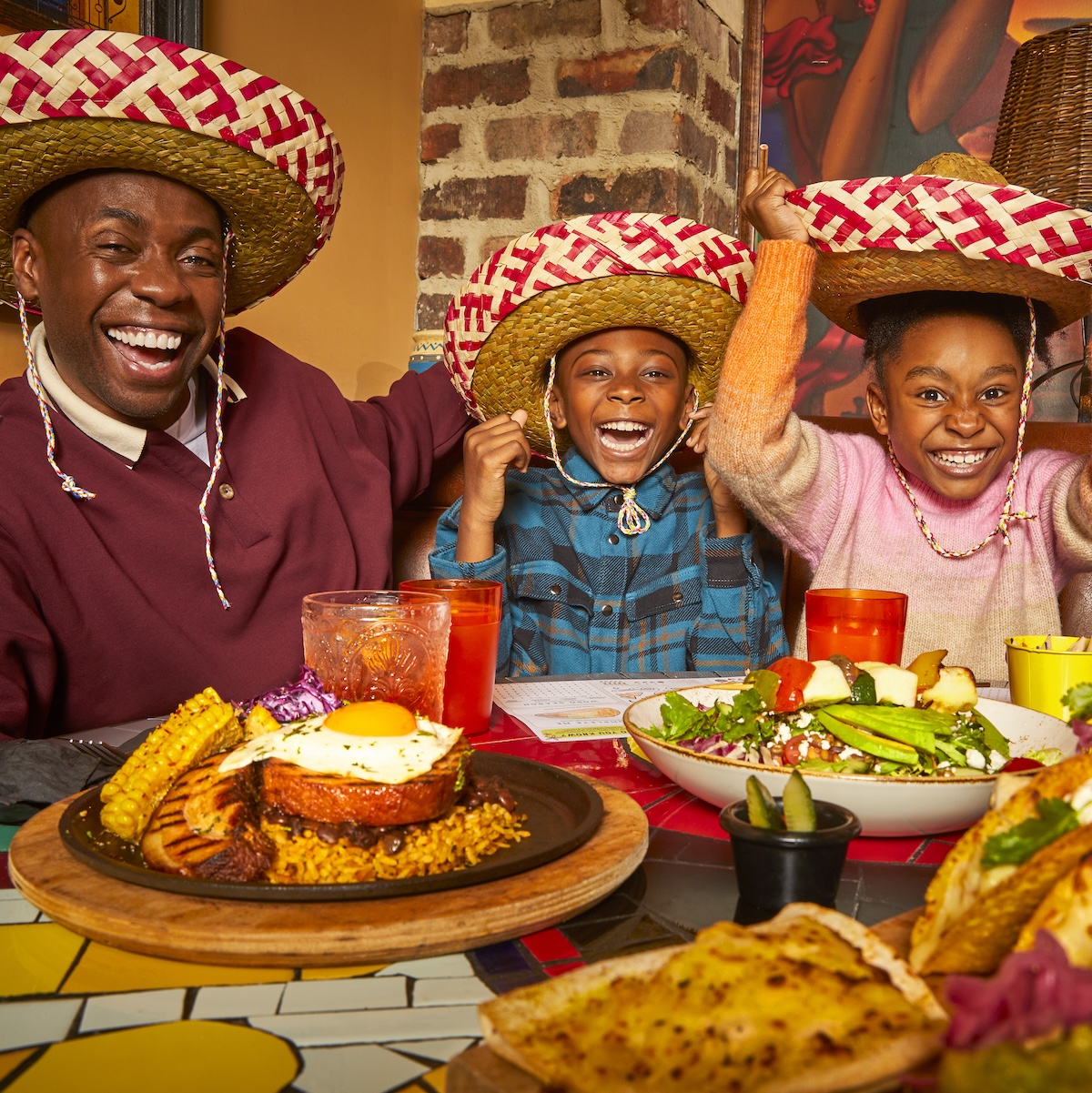 Man and two children eating a meal with hats on