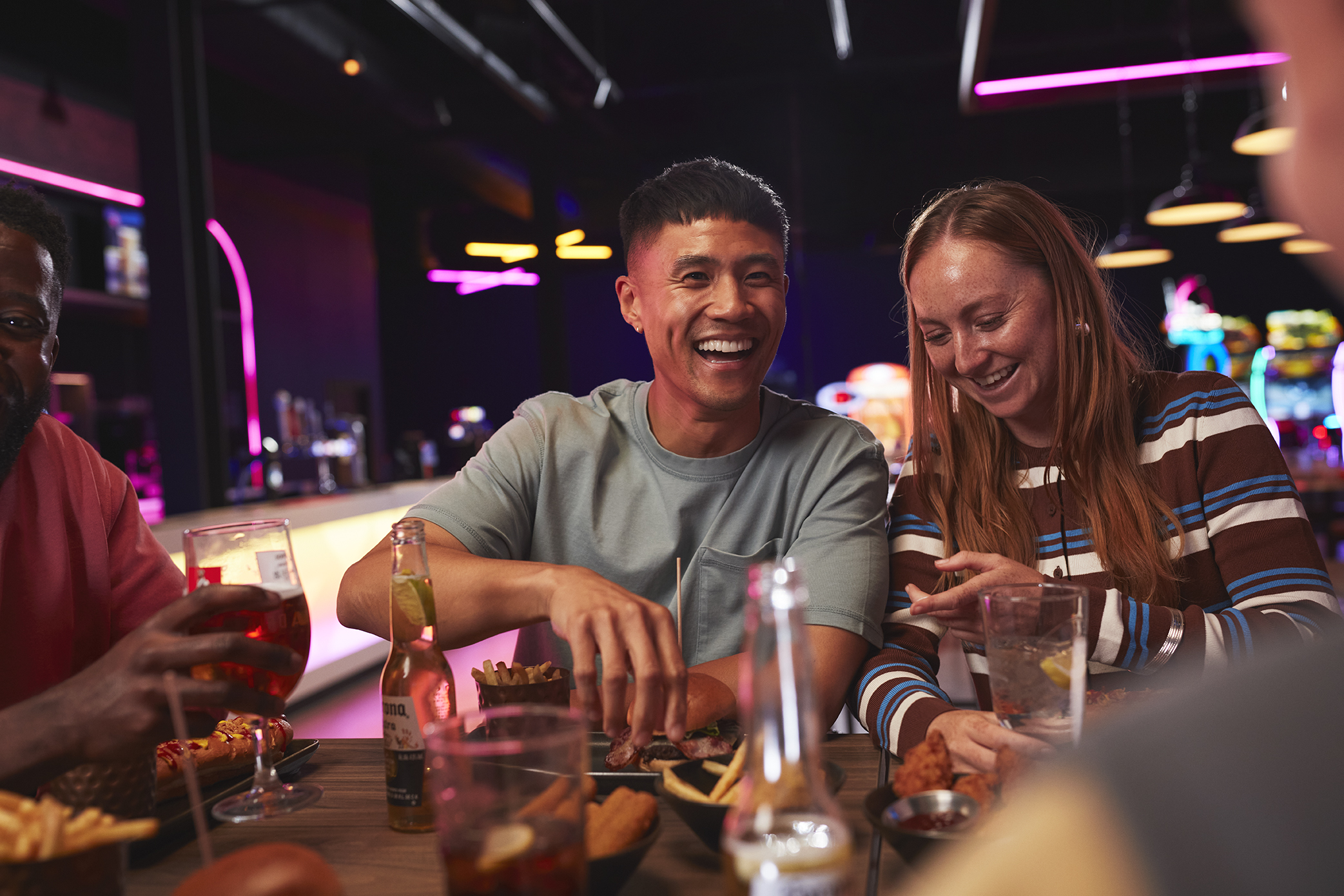 A man and a woman are pictured enjoying burgers and fries at a Hollywood Bowl location