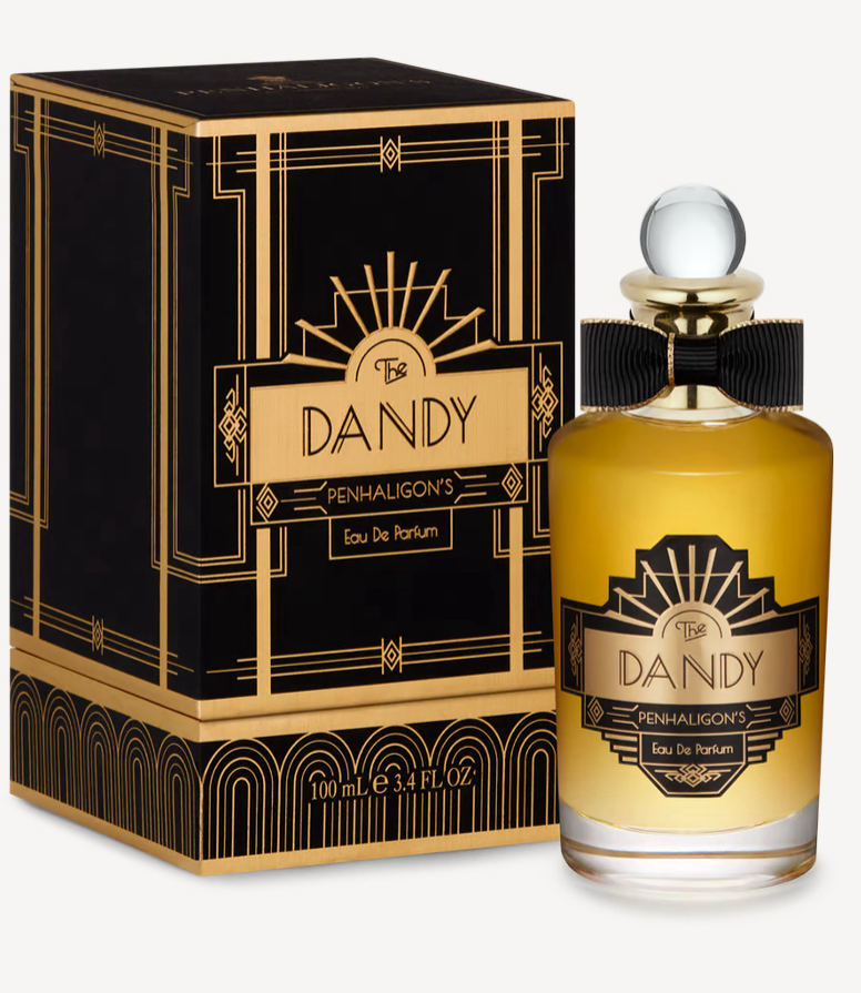 The Dandy perfume, gold in a glass bottle, stood next to a black box 