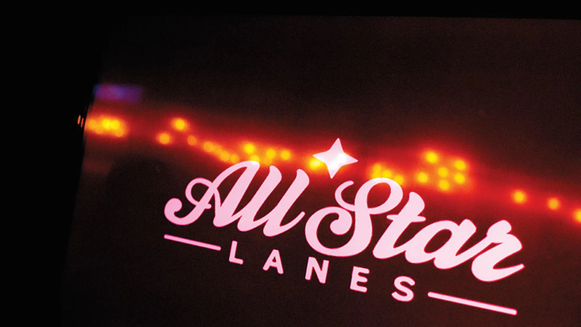 Neon pink 'All Star Lanes' sign with a star detail.