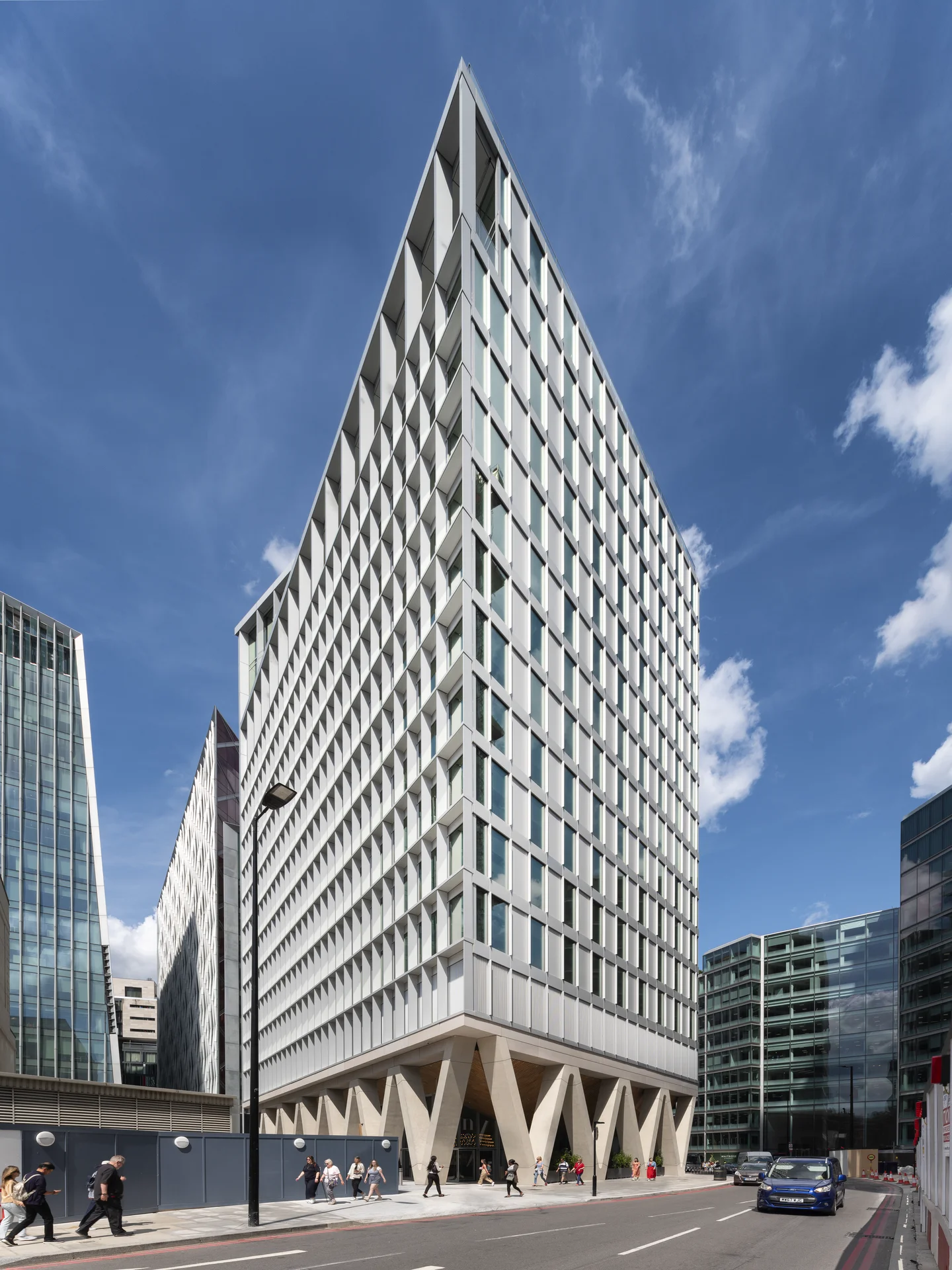 Modern glass office tower with triangular architecture and people on the street