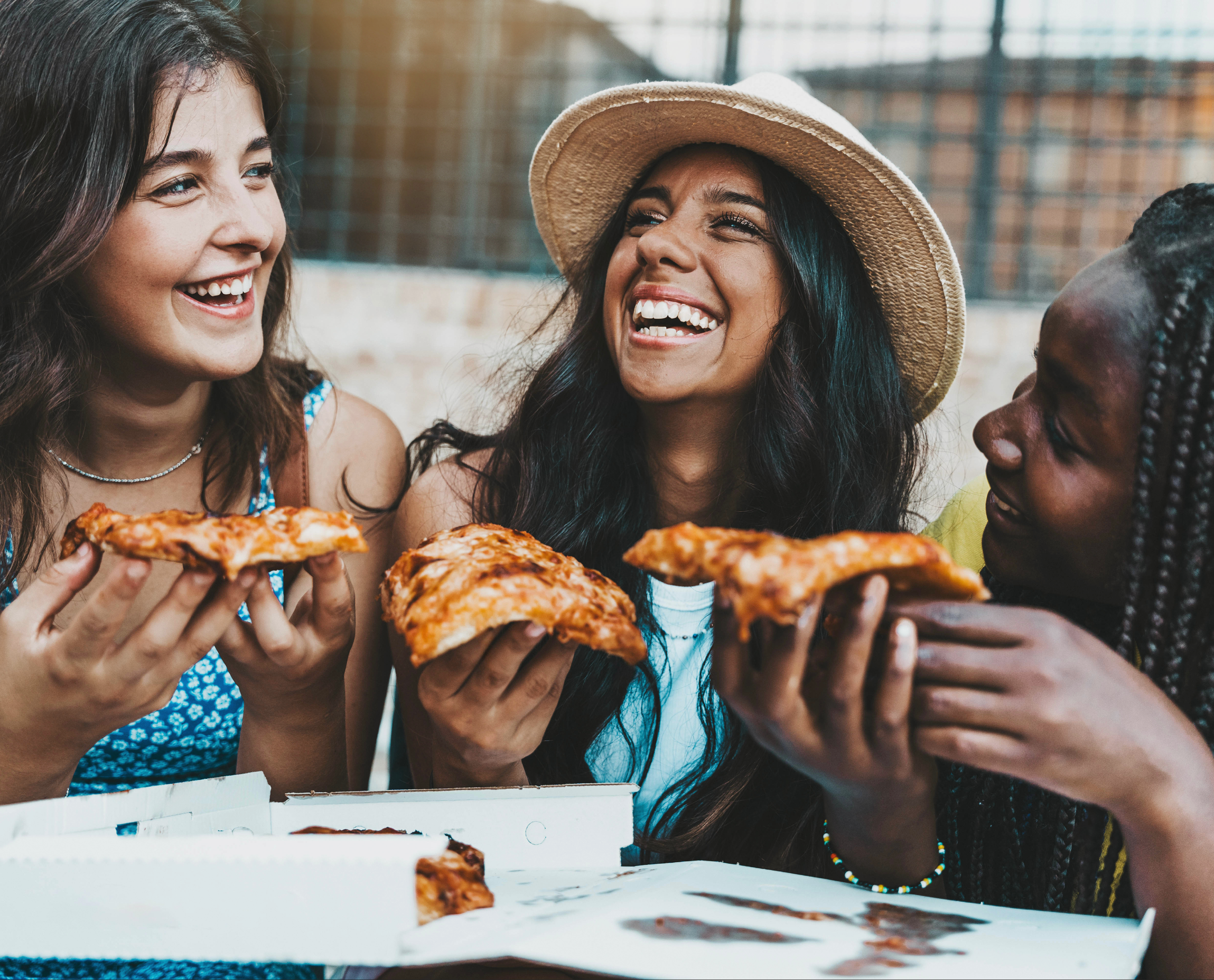 Friends smile together while holding a slice of pizza each