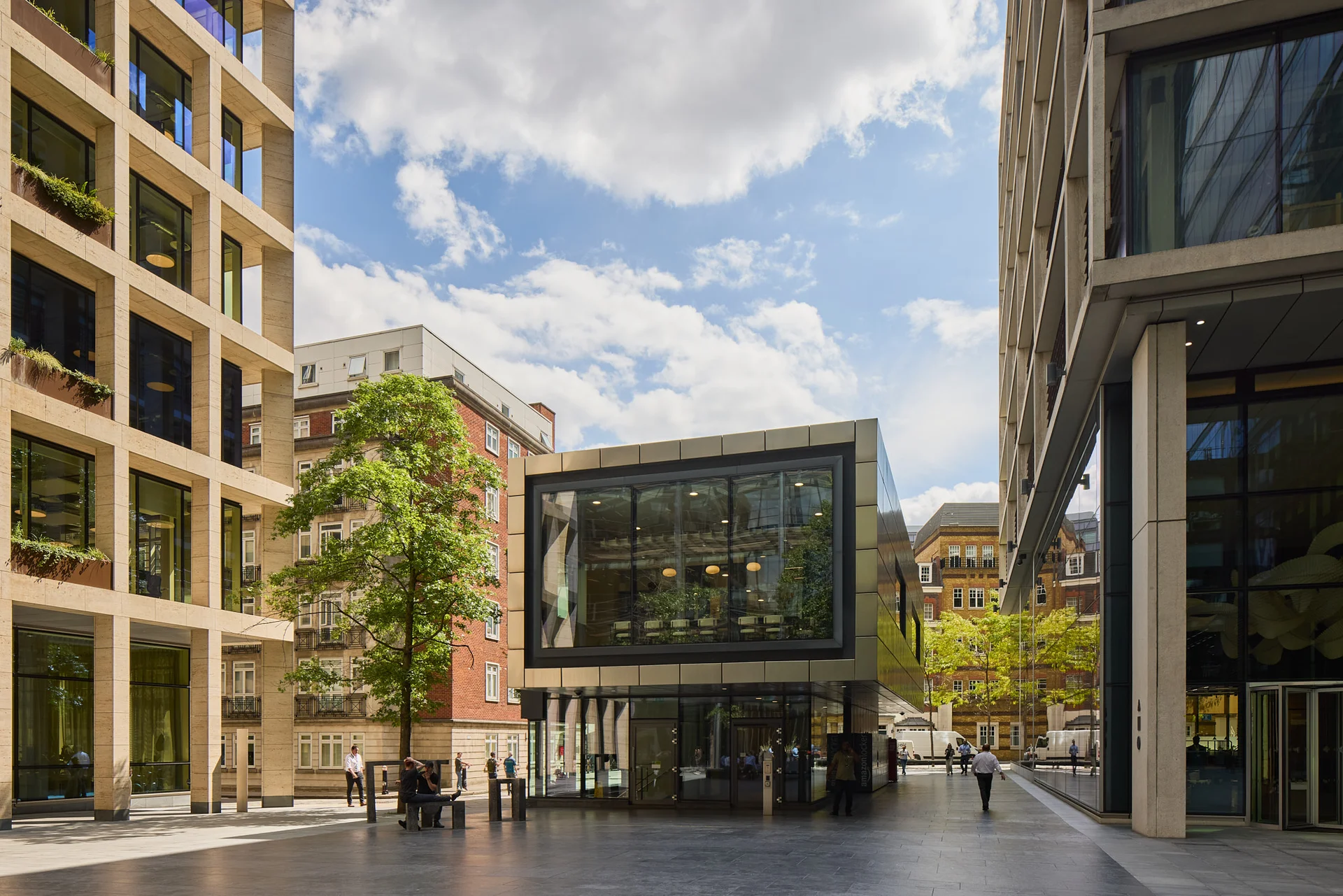 Modern glass office building with reflections and a tree in the courtyard