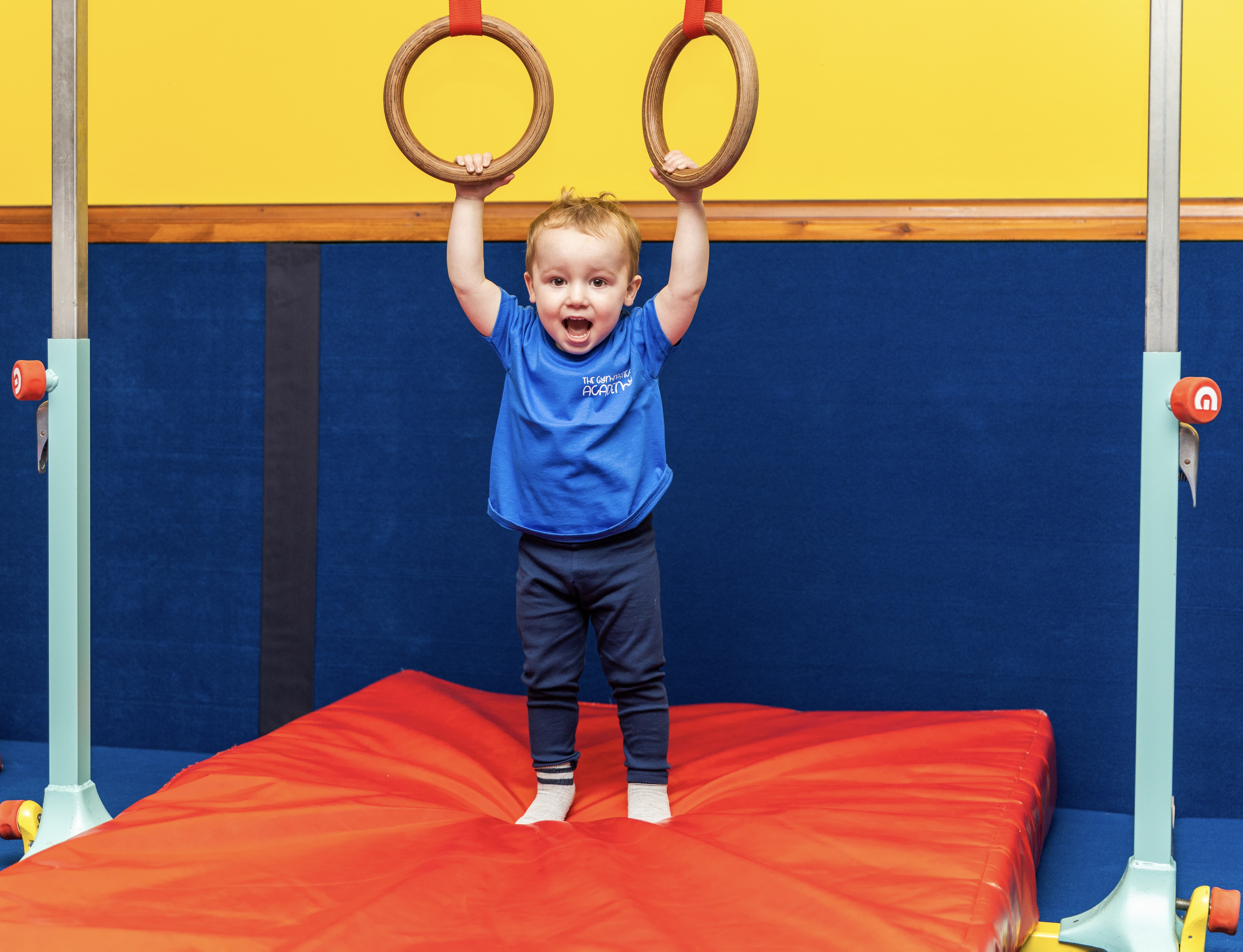 Toddler on gym mat wearing blue t-shirt