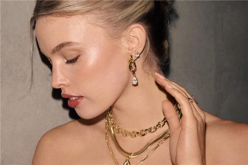 A blonde woman wearing gold necklaces and earrings