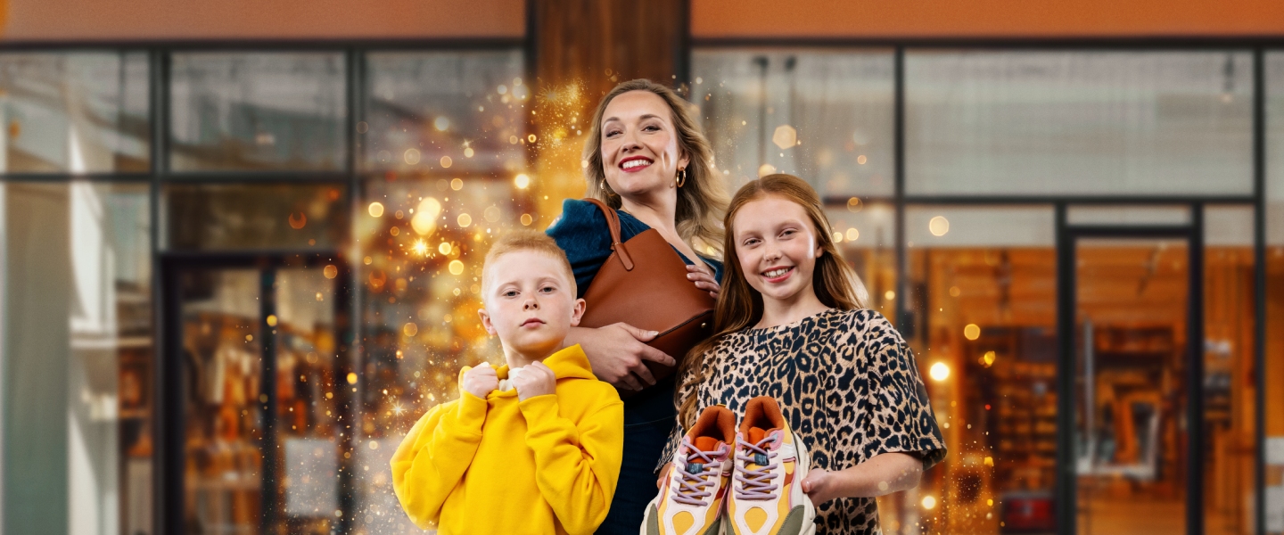 A mother, son and daughter stood in front of a store holding a new pair of trainers