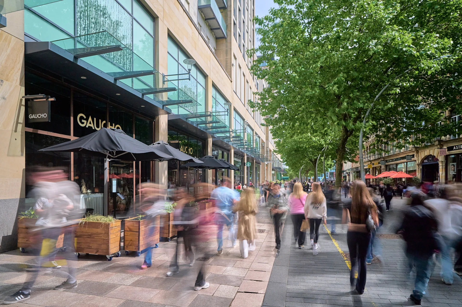 Exterior street view near St David's Cardiff. Shows outdoor dining at Gaucho and a busy, tree-lined pedestrian area.