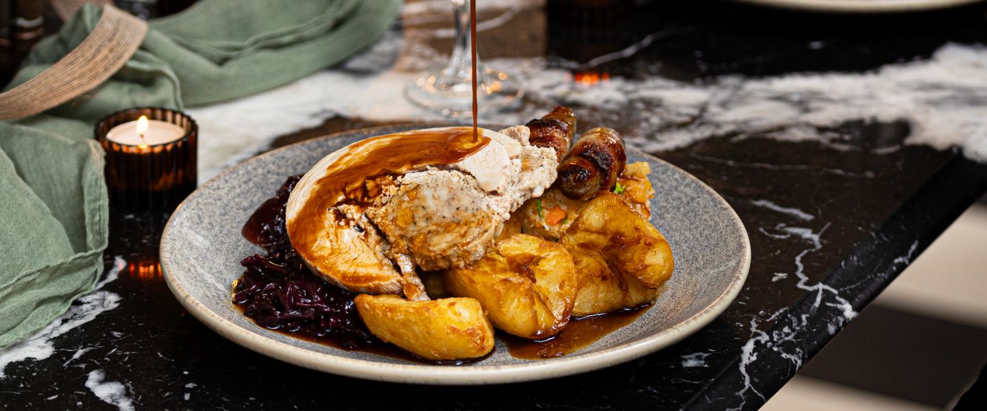 A full Christmas dinner on a plate with gravy being poured on top