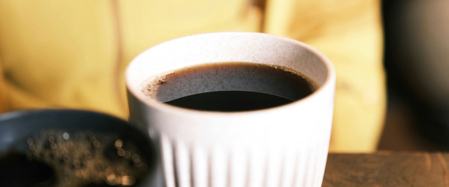 A reusable cup on a table full of coffee