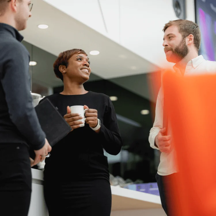 Three people having a conversation in a modern office setting