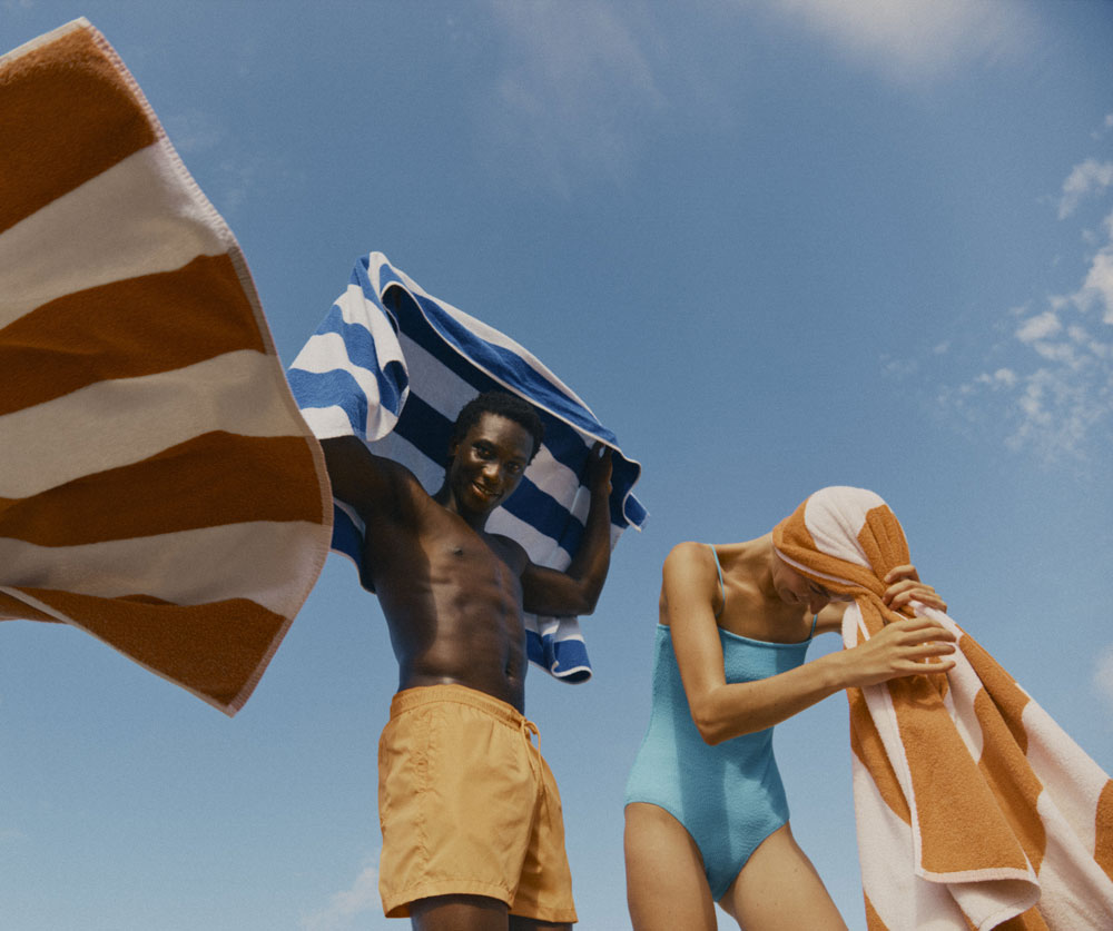 Man and woman in swimwear with towels in the sun
