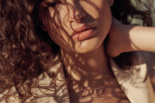 The lower half of a woman's face, draped in her brown curly hair