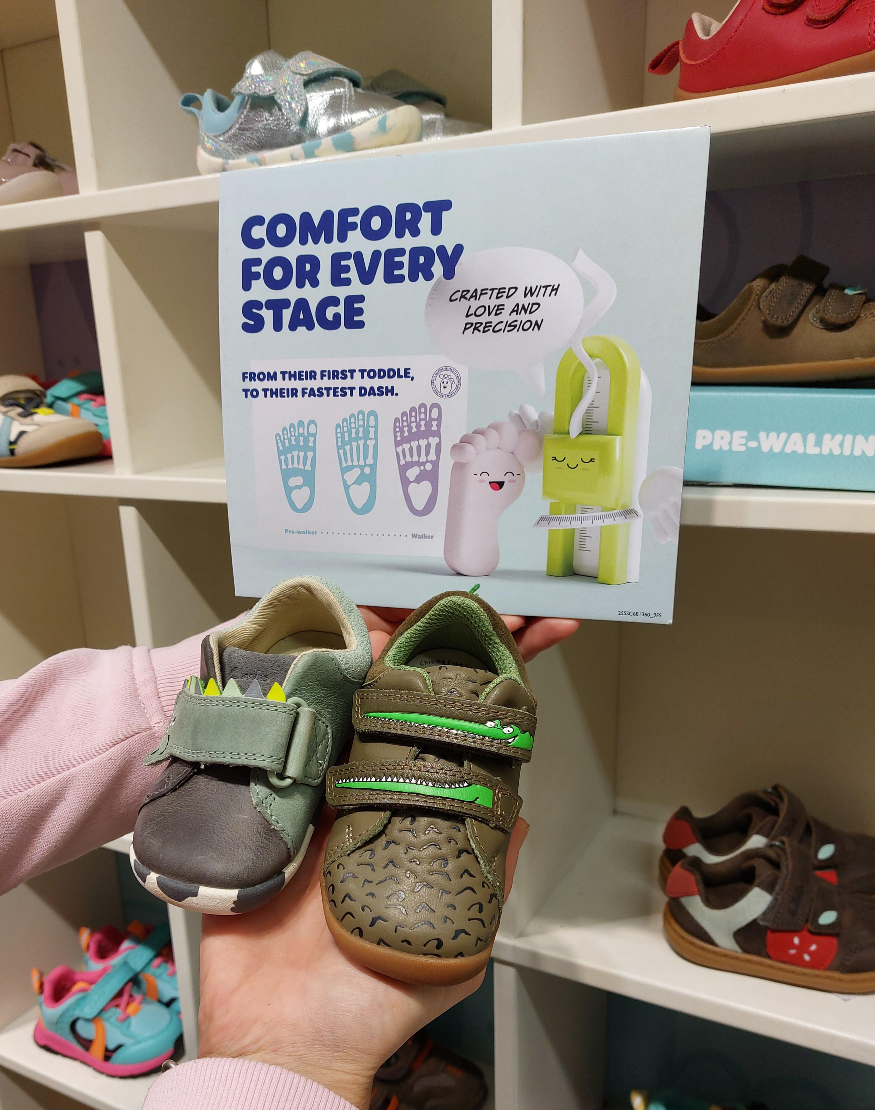 A hand displaying cute fun toddler shoes with velcro