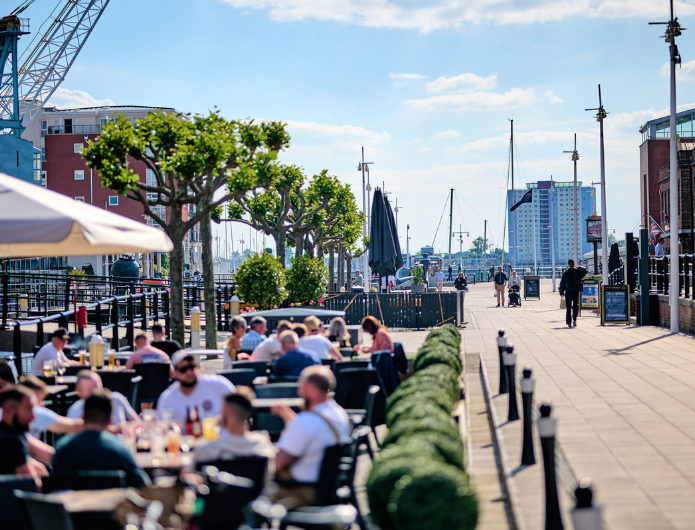 An image of people dining outside at Gunwharf Quays on a sunny day