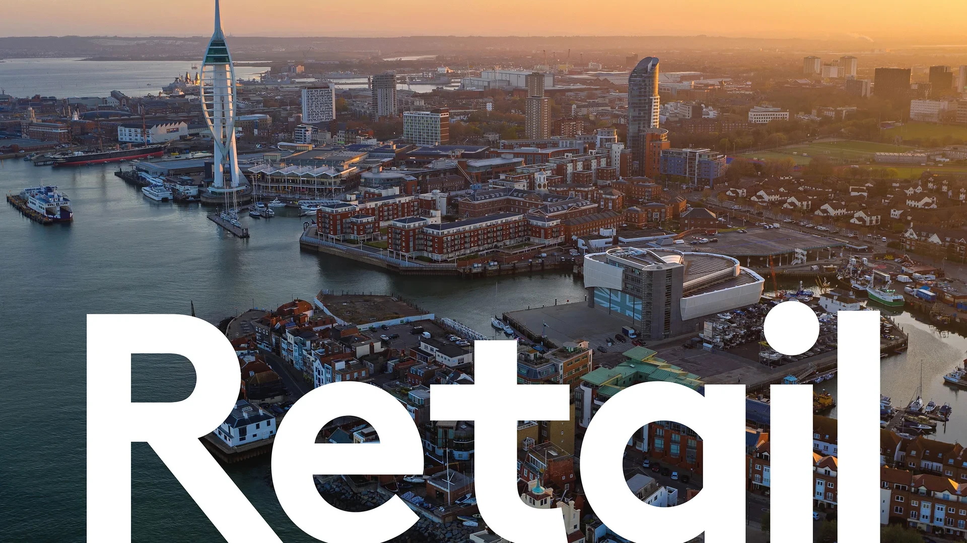 Aerial cityscape of a waterfront area at sunset, with "Retail" text overlay