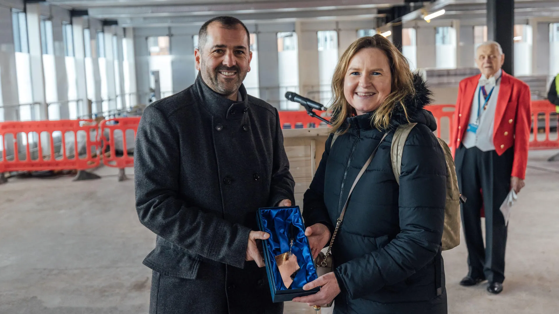 Man and woman holding a blue box with a medal inside.