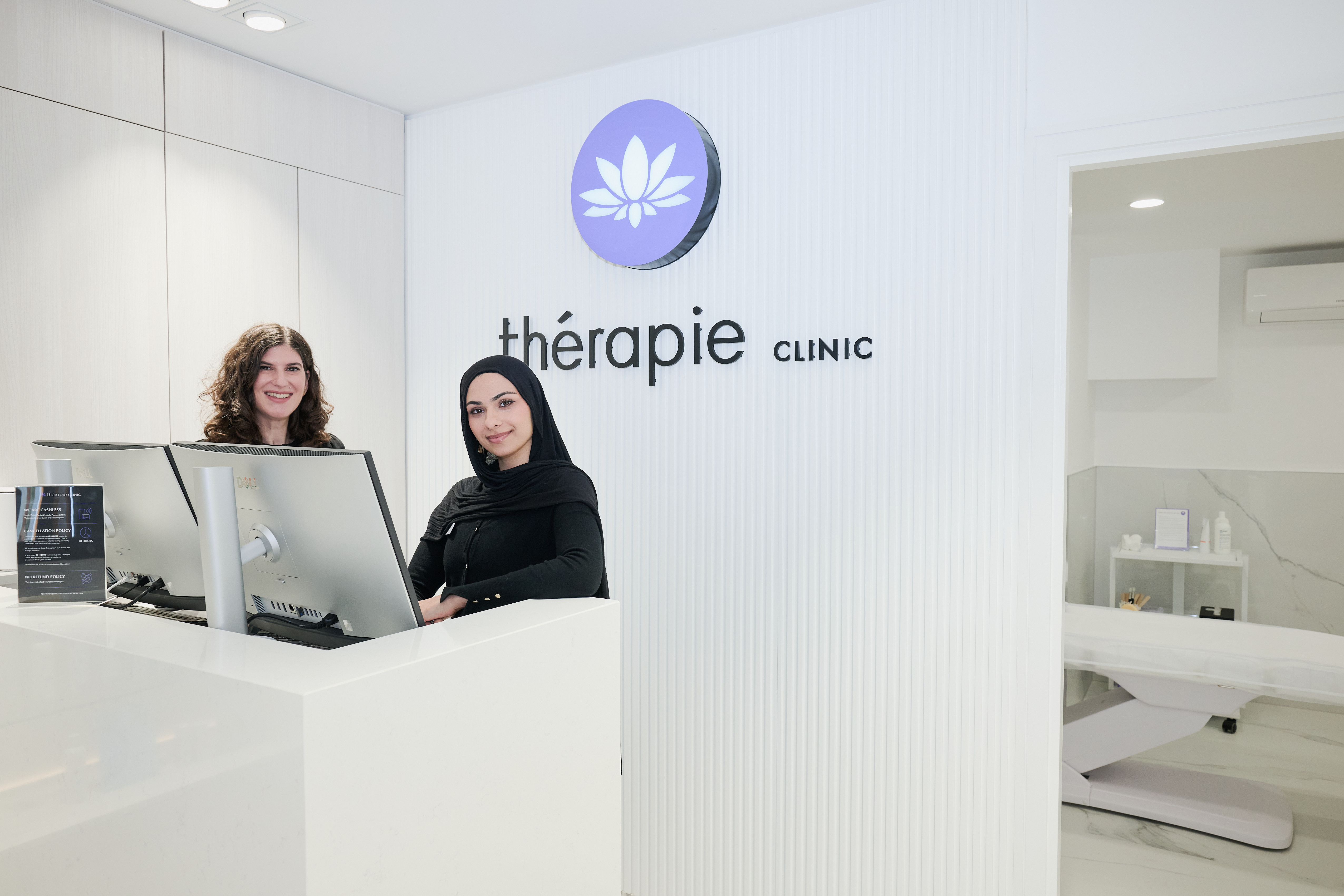 The entrance of Therapie Clinic, showing two female receptionists smiling at the camera.