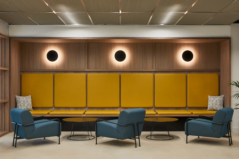 Modern office lounge with yellow bench seating and blue chairs