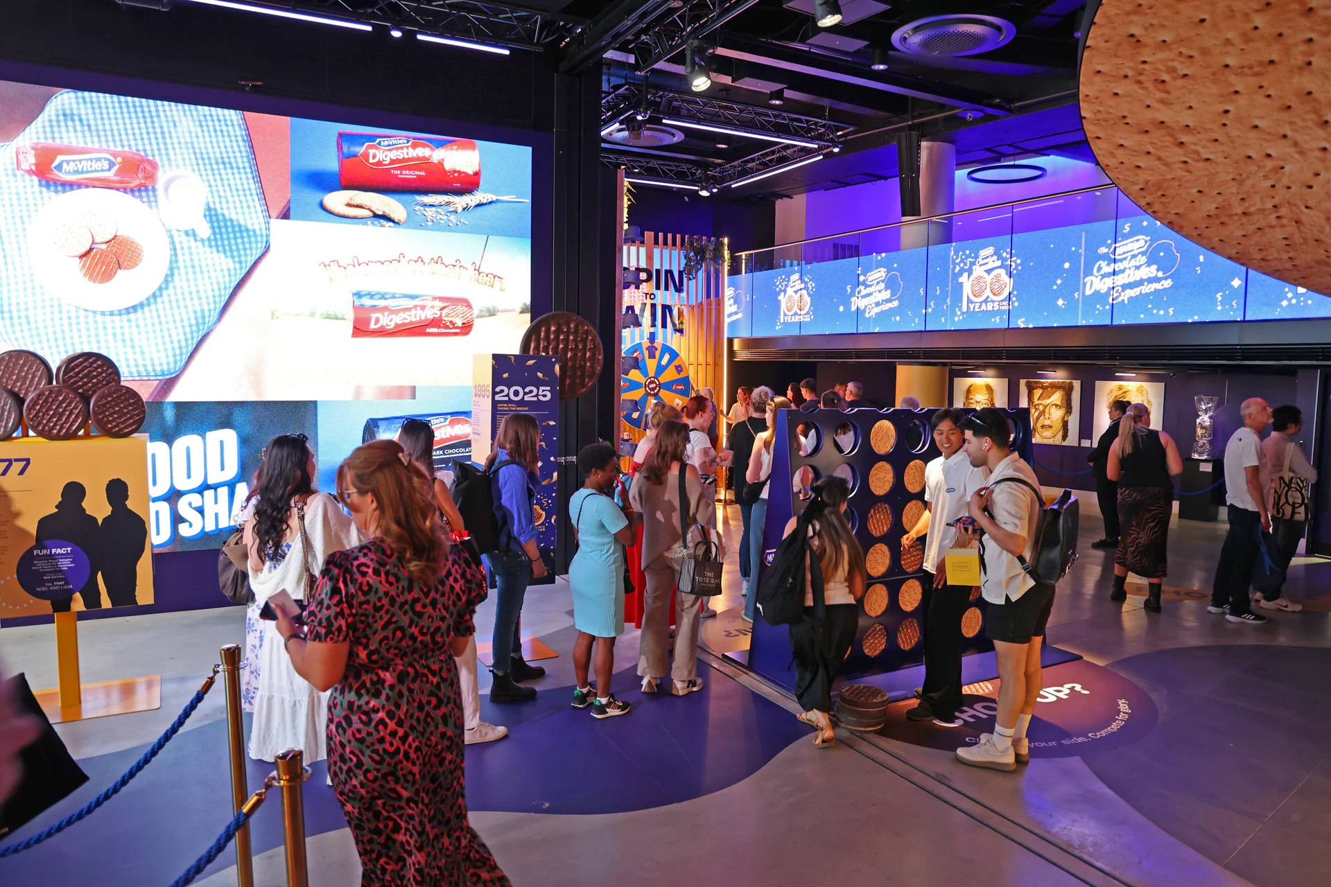 Esports area featuring racing simulator setups, fans, and staff in a blue-lit environment.