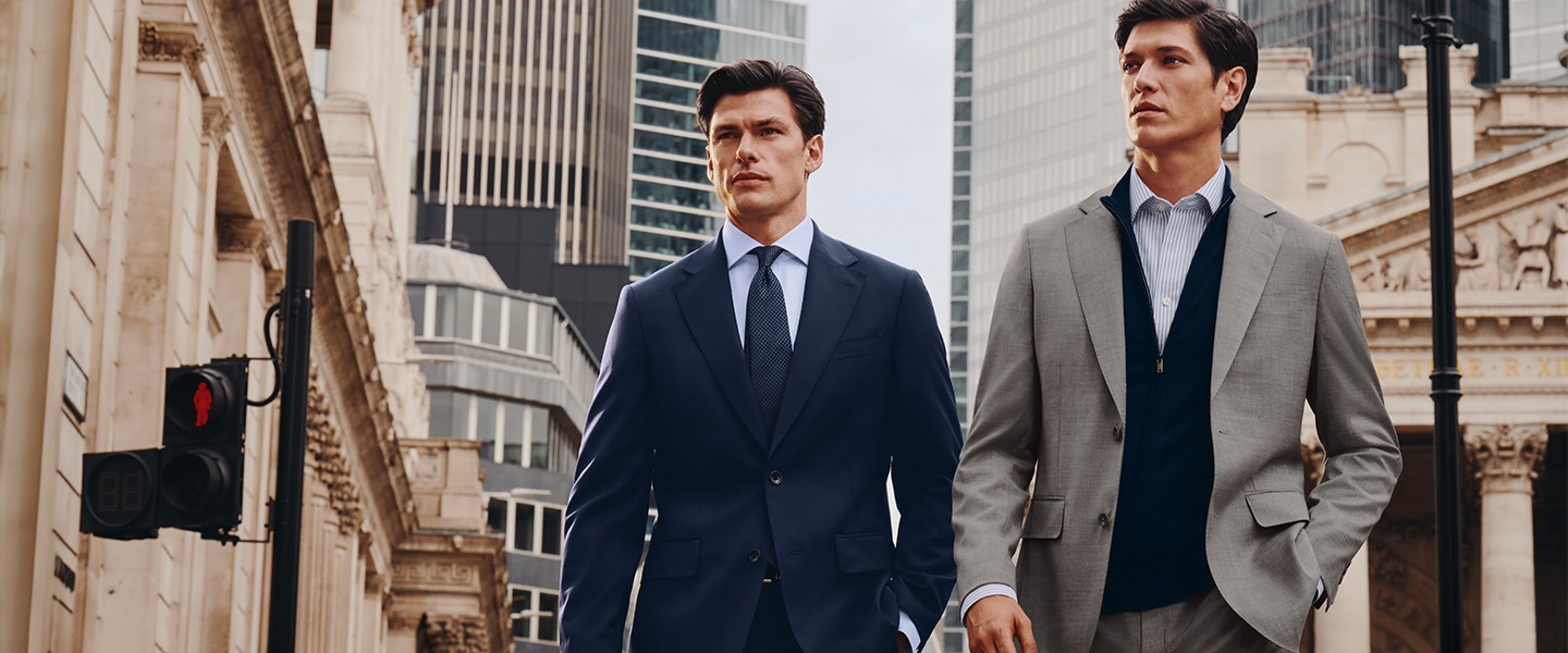 Two men walk down the street wearing suits