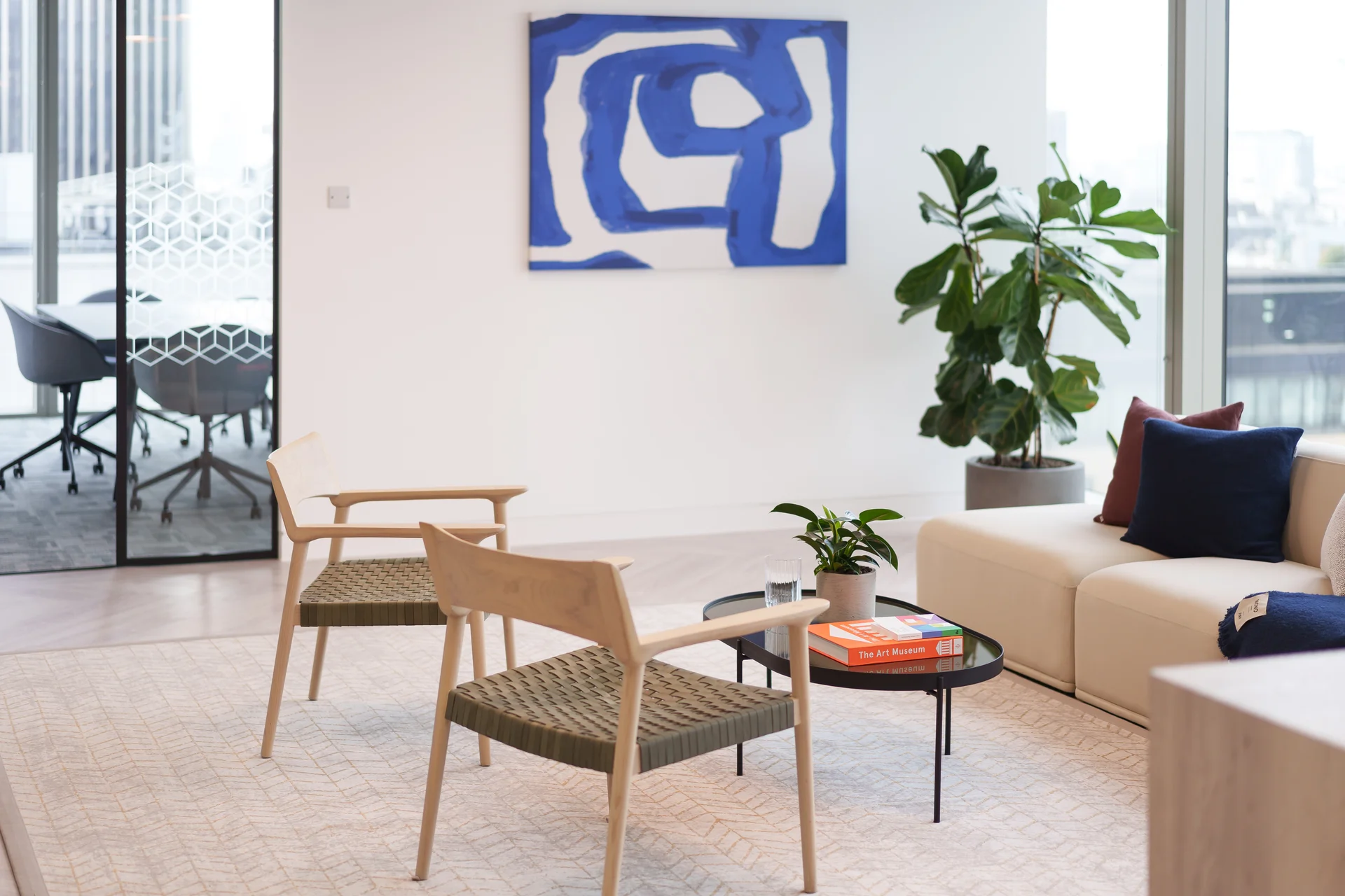 Contemporary lounge with light chairs, a sofa, plants, and abstract artwork