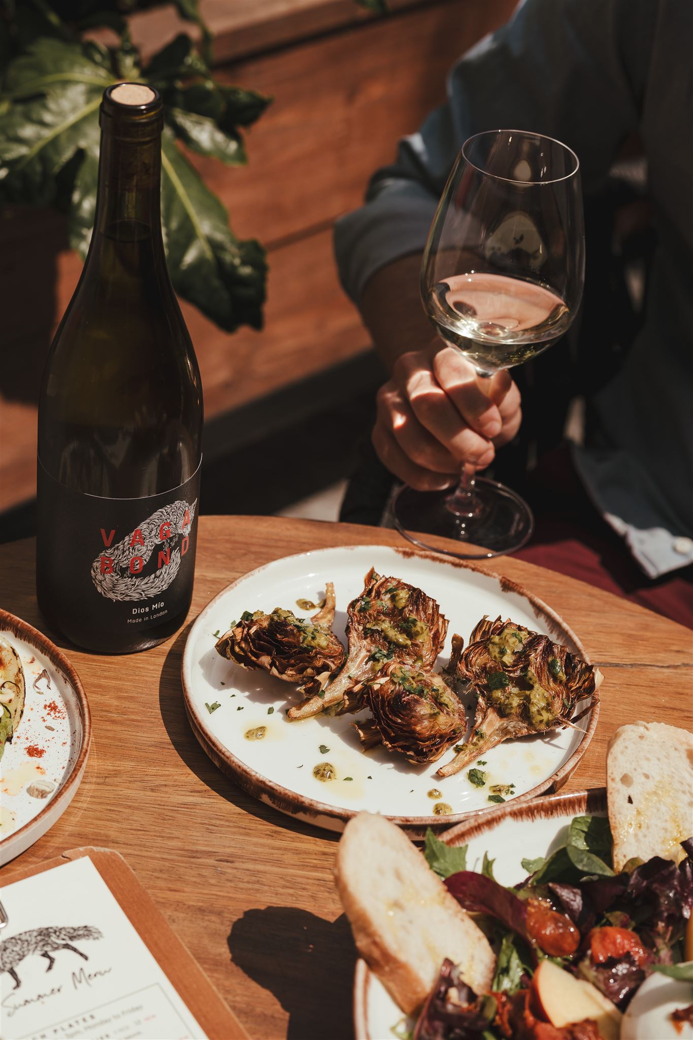 Meat on a plate next to a bottle of wine