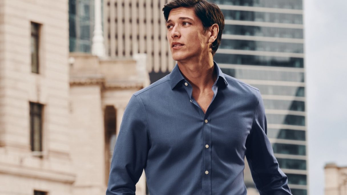 A man wearing a blue shirt outside in a city