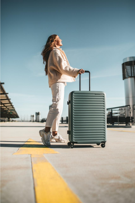 A woman carrying a suitcase waits outside for an aeroplane 