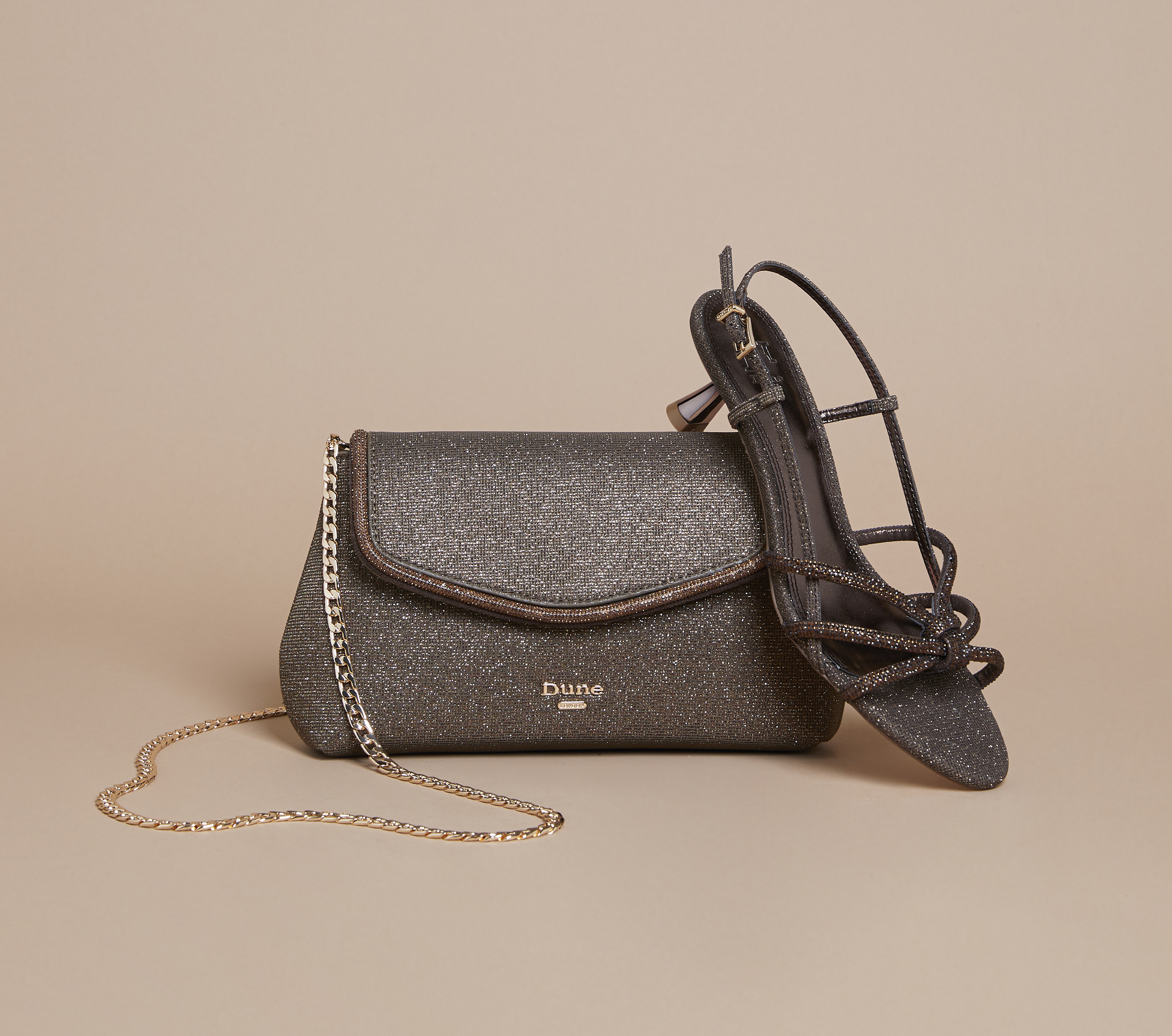 A stylish black sandal leant against a black leather handbag