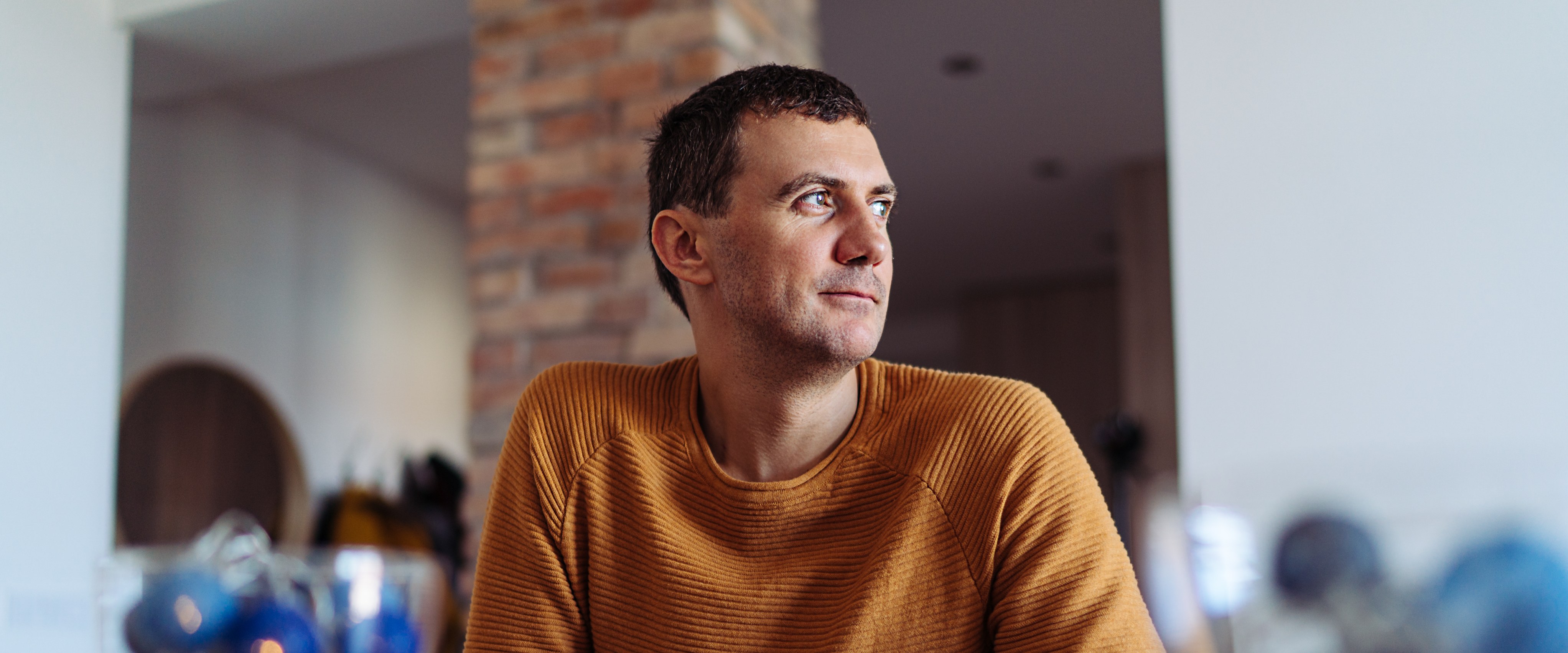 Portrait image of a man sitting at a table looking into the distance 
