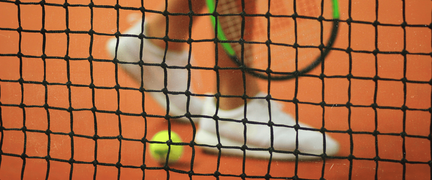 A tennis ball and racquet through a tennis net