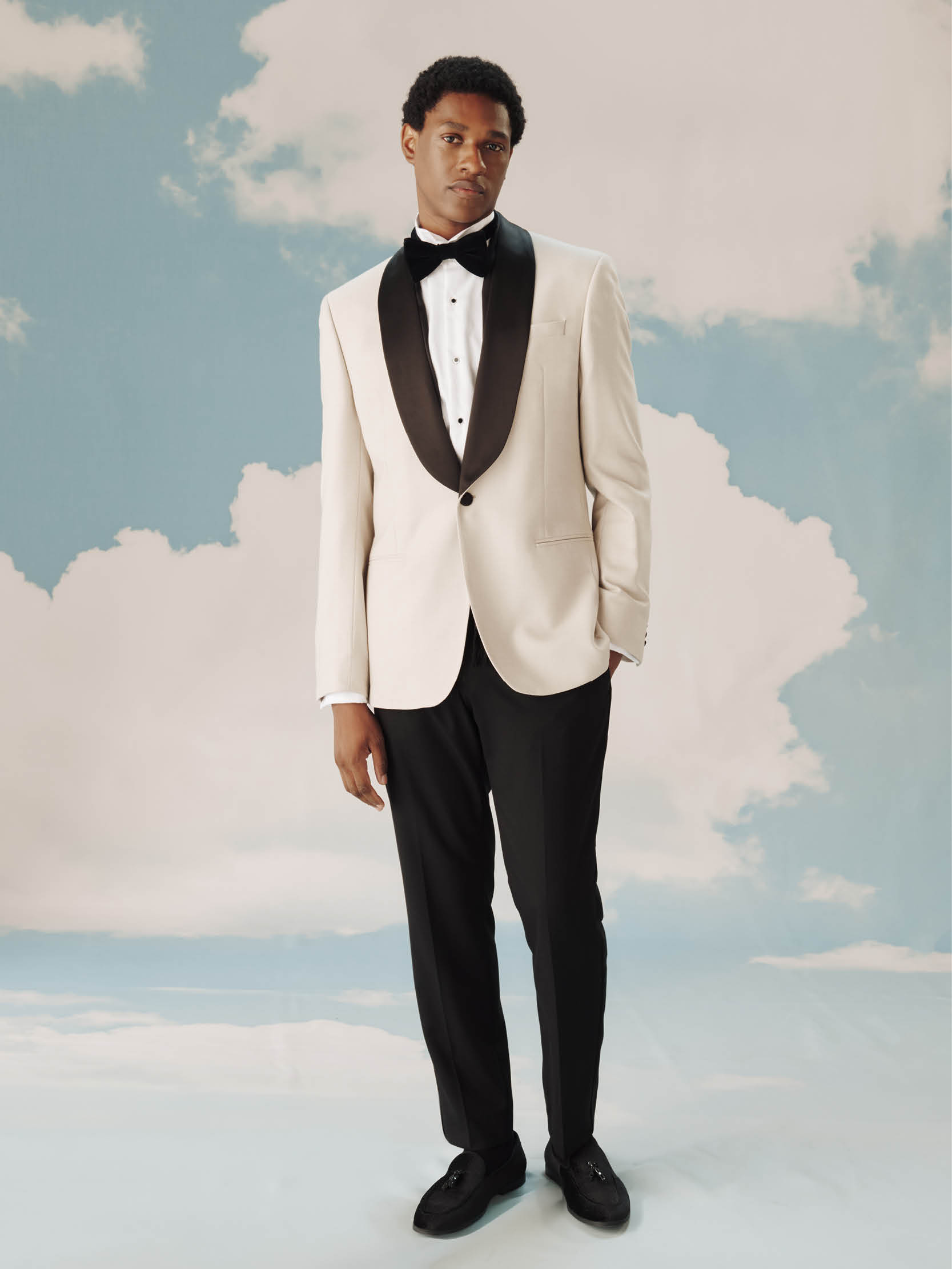 A model wearing a tuxedo with white jacket and bow tie