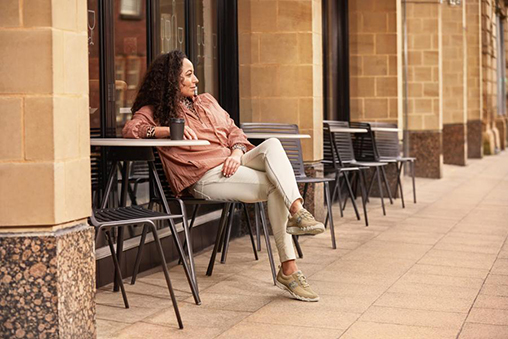 A woman sat at a cafe table in comfortable shoes