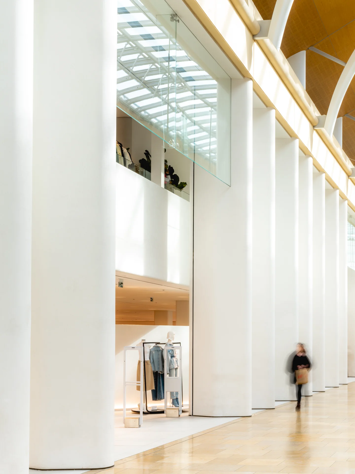 Close-up of St David's Cardiff's interior architecture. Features white columns, a minimalist store display, and high windows.