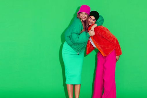 Two friends hugging dressed in bright green and bright pink