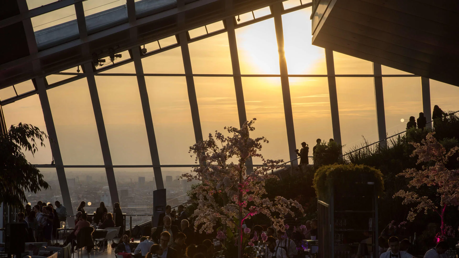 Rooftop bar with city skyline sunset view and people dining.
