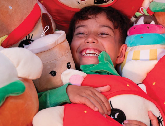 Boy amongst soft toy cushions