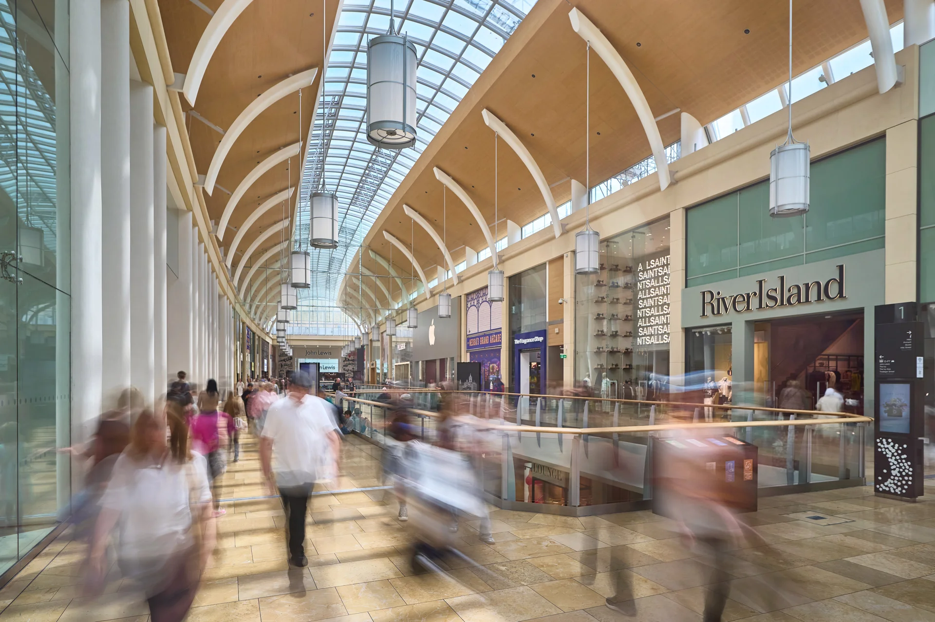 St David's Cardiff mall interior with River Island & AllSaints. Features a vaulted glass roof and busy shoppers.