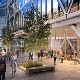 A busy **pedestrian plaza** outside a glass-fronted building, showing an outdoor café area and people walking through a landscaped area with birch trees.