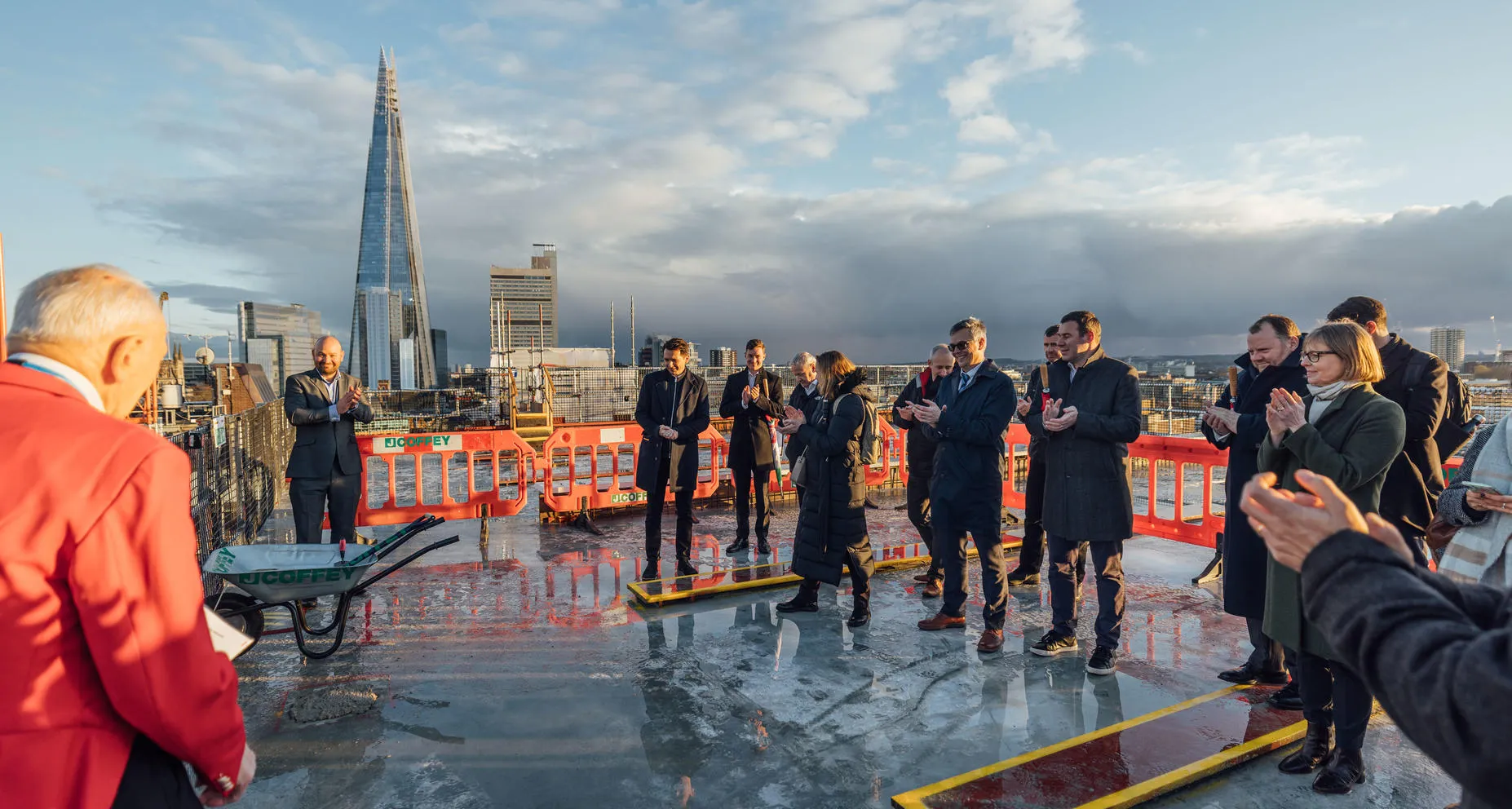 Group of people clapping on a rooftop with a city skyline and skyscraper in the background.