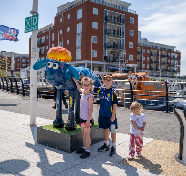 Three young children stood by shaun the sheep model
