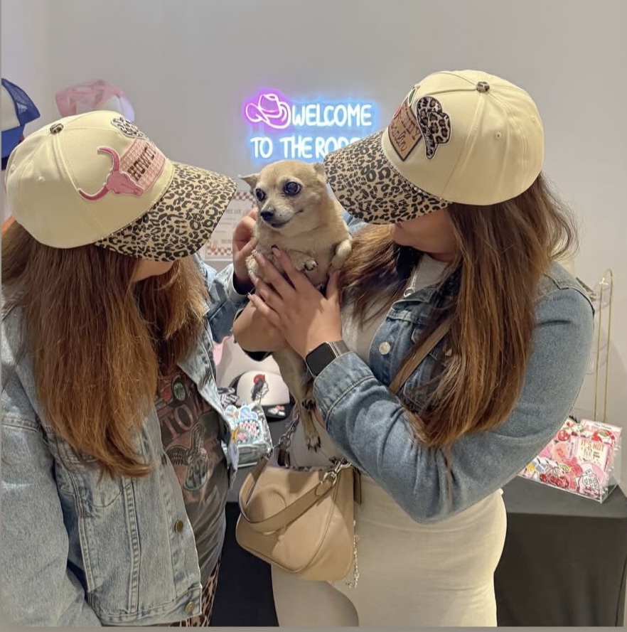Two women in trucker hats holding a dog
