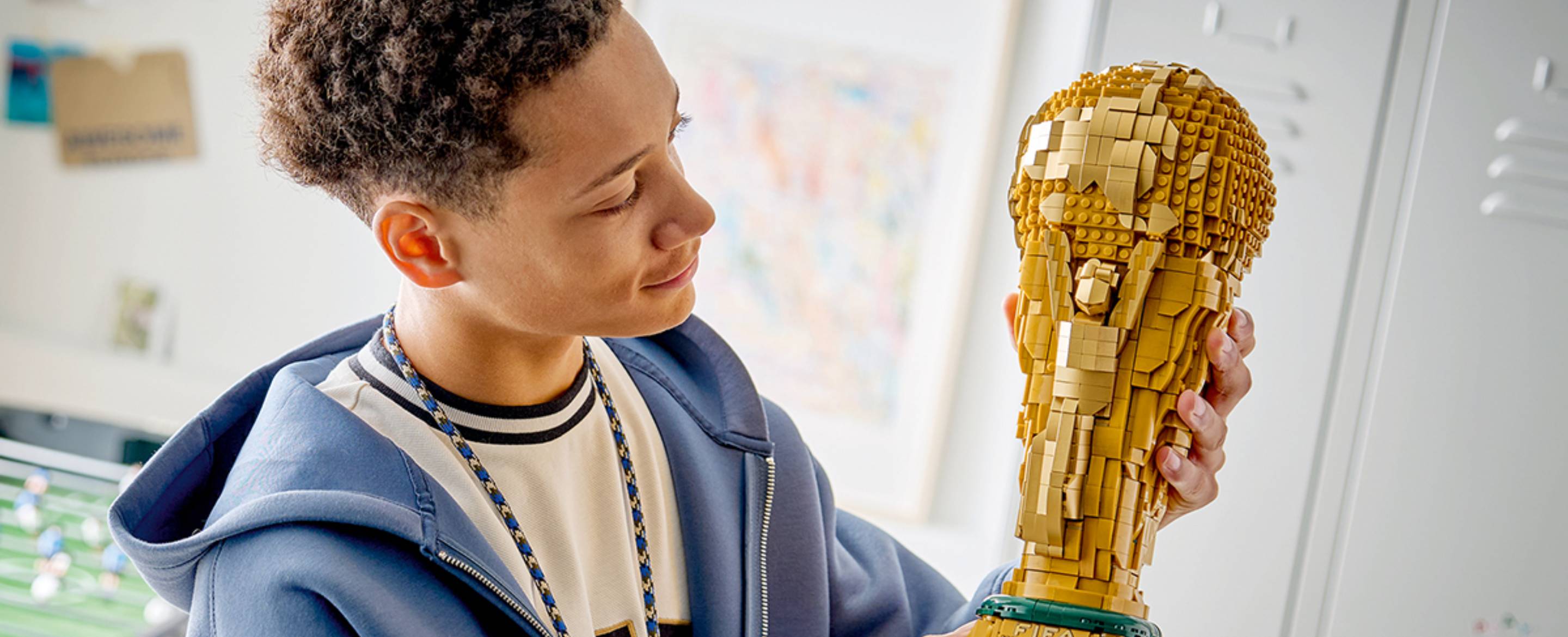 A teenager holding the LEGO® Editions World Cup Trophy