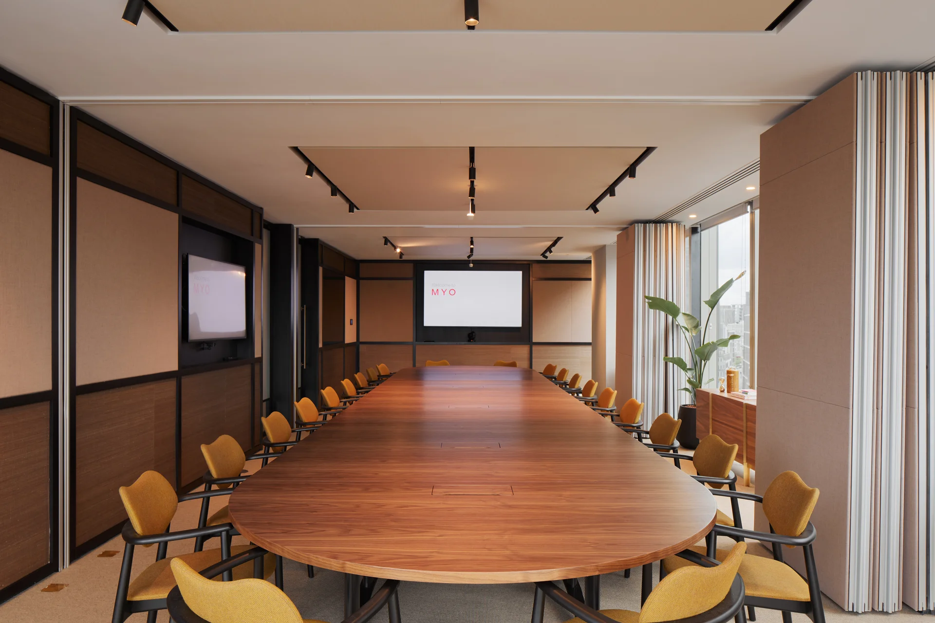 Large boardroom with oval wooden table and mustard chairs