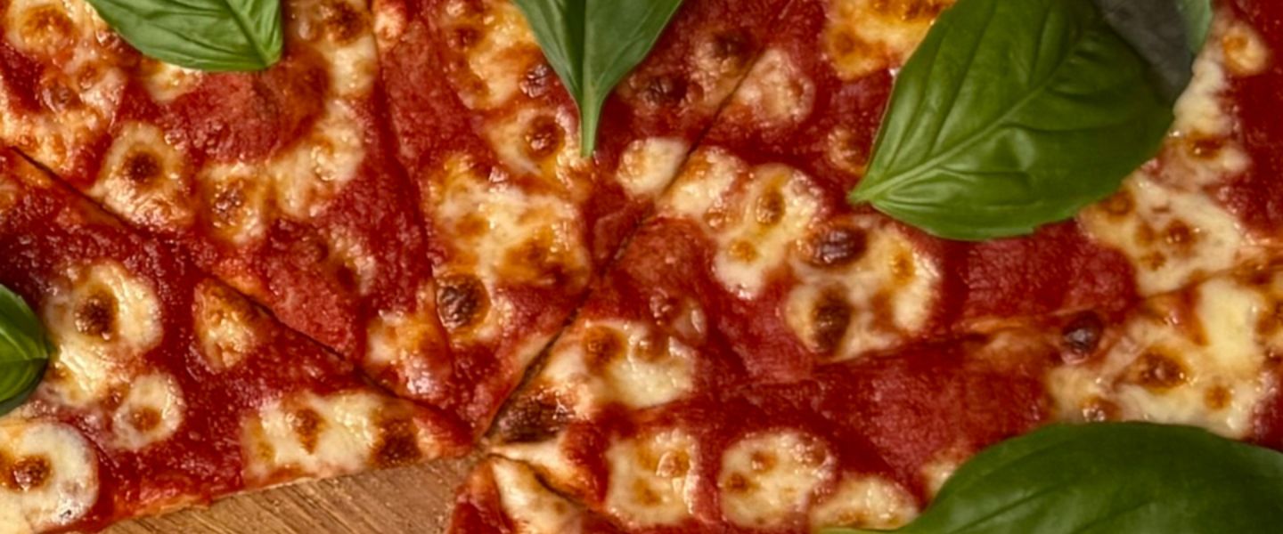 A cheese pizza topped with basil leaves